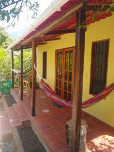 a hammock on the porch of a house at Bosque Azul Picaflor in Minca