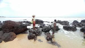 two people standing on the rocks on the beach at Saly LRAD Le village in Ngaring
