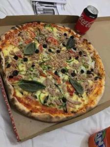 une pizza assise dans une boîte sur une table dans l'établissement Nouveau Appartement Avec Un Parking Gratuit, à La Marsa