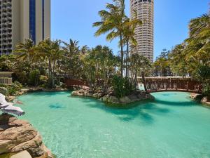 a pool of water with palm trees and a bridge at Crown Tower by Serain Residences in Gold Coast