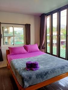 a bedroom with a large bed with purple sheets and windows at Cliff View Bungalows in Ko Chang