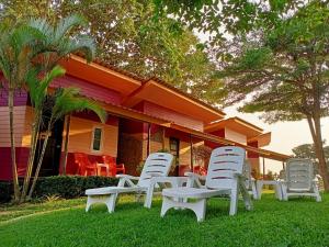 a group of white lawn chairs in front of a house at Cliff View Bungalows in Ko Chang +67 photos