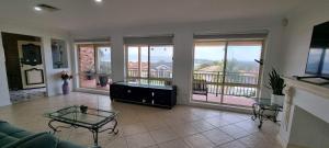 ein Wohnzimmer mit einem Sofa, Tischen und Fenstern in der Unterkunft Shellharbour. Ocean, lake and mountain view in Shellharbour