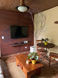 ein Wohnzimmer mit Tisch und Fernseher in der Unterkunft Petite Maison - Dona Belandira in Campos do Jordão