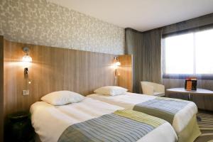 a hotel room with two beds and a window at Mercure Angers Centre de Congrès in Angers