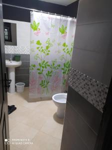 a bathroom with a shower curtain with plants and a toilet at Hotel La coline in Beni Mellal