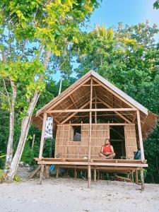 a person sitting in a house on the beach at Biryei Homestay in Pulau Birie