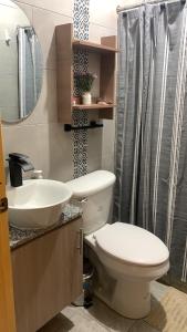 y baño con aseo, lavabo y ducha. en Garzota Garden PB, en Guayaquil