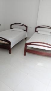 two beds sitting in a room with white floors at Villa Myrian in Villanueva
