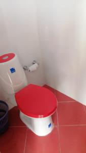 um WC vermelho com uma tampa vermelha numa casa de banho em Villa Myrian em Villanueva