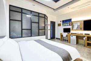 a bedroom with a bed and a desk and a television at Hoengseong Haru Self check-in Hotel in Hoengsong