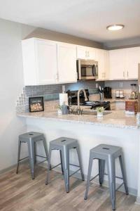 a kitchen with three stools sitting at a counter at WOO LOFT- King Bed- Downtown BHM in Birmingham