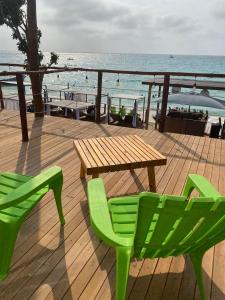 eine Holzterrasse mit einem Tisch, Stühlen und Meerblick in der Unterkunft SUNSET BEACH in Playa Blanca