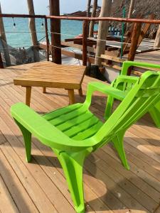 two green chairs and a table on a deck at SUNSET BEACH in Playa Blanca
