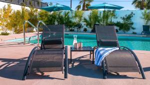 einen Tisch und zwei Stühle neben einem Pool in der Unterkunft Onsen Hotel and Spa in Desert Hot Springs