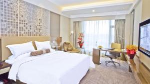 a hotel room with a large white bed and a desk at Juntai Hotel Xiamen in Xiamen
