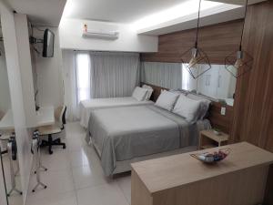 a hotel room with two beds and a desk at Tambaú Flat Belo Mar - Cabo Branco - ANÚNCIO NOVO in João Pessoa