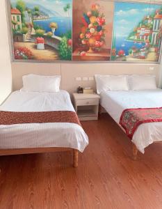 two beds in a room with paintings on the wall at 好金門民宿 in Jincheng