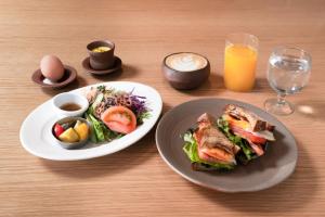 a table with two plates of food and a bowl of salad at TSUGU Kyoto Sanjo by THE SHARE HOTELS in Kyoto