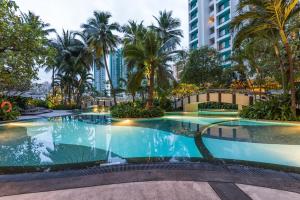 uma grande piscina com palmeiras e edifícios em Chatrium Residence Sathon Bangkok em Banguecoque