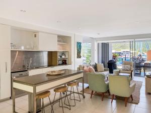 Blue on Blue Apartment 316 في خليج نيللي: مطبخ وغرفة معيشة مع طاولة وكراسي