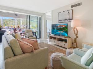 Blue on Blue Apartment 316 في خليج نيللي: غرفة معيشة مع أريكة وتلفزيون بشاشة مسطحة