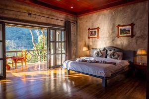 a bedroom with a bed and a sliding glass door at Resort Maison de Nongkhiaw in Nongkhiaw