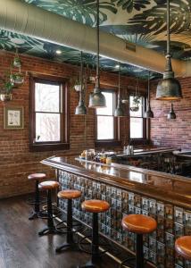 a bar with brown stools and a brick wall at ARRIVE Wilmington in Wilmington