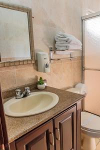 ein Badezimmer mit einem Waschbecken, einem WC und einem Spiegel in der Unterkunft Art Hotel Boutique in San Pedro Sula
