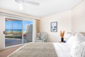 a bedroom with a bed and a chair and a window at Mariners 1 in Mollymook
