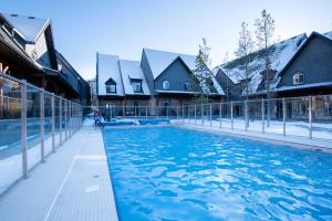 a swimming pool with blue water in front of houses at Mountain Chalet at Mystic Springs, 2BR, 2BA, Heated Pool, Hot Tub! in Canmore