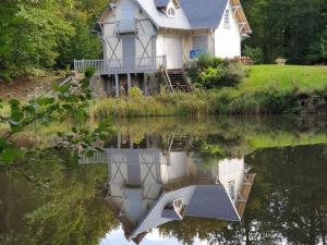 a house with its reflection in the water at Retraite Paisible au Cœur de la Forêt de Rambouillet avec Étang Privé et Charme Authentique - FR-1-527-8 in Clairefontaine