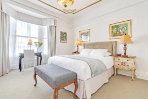 a bedroom with a large white bed and a desk at Cornell Hotel de France in San Francisco