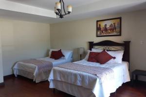1 dormitorio con 2 camas con sábanas blancas y almohadas rojas en Vila Krista, en Quetzaltenango