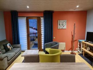 een woonkamer met een bank en stoelen en een tv bij Le Rouge Gorge Curieux in Vresse-sur-Semois