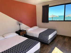 two beds in a room with a view of the ocean at Stella del Mar in San Felipe