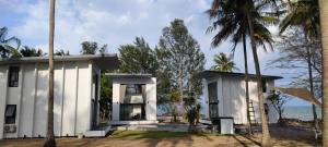 een wit huis met palmbomen voor de oceaan bij Meet Up Villa 