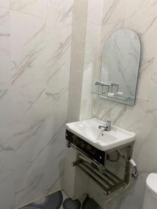 a white bathroom with a sink and a mirror at Wisma Jannatun Naim Lampung in Lampung