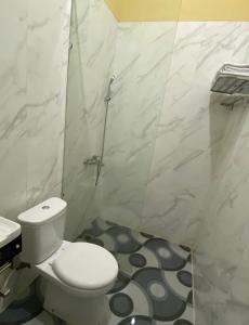 a white bathroom with a toilet and a shower at Wisma Jannatun Naim Lampung in Lampung