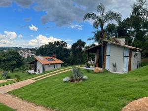 a house on a grassy hill with a palm tree at Chalé Village Jângal in Machado