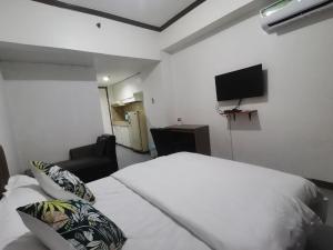 een slaapkamer met een wit bed en een flatscreen-tv bij TemporaryHome -susan in Manilla