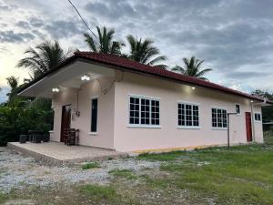 una pequeña casa blanca con techo rojo en Joe’s Homestay Raub Phg, en Raub