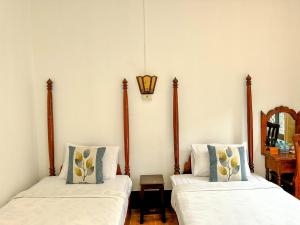 2 Betten in einem Zimmer mit einer Lampe an der Wand in der Unterkunft Chaliya Boutique Garden in Luang Prabang