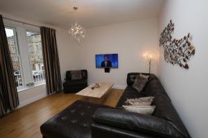 a living room with a leather couch and a table at Dalry House Residence in Edinburgh