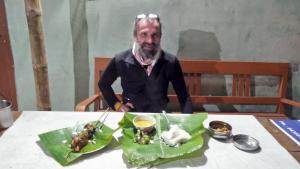 a man sitting at a table with a plate of food at Subansiri lodge in Majuli
