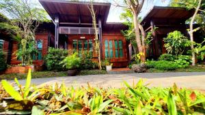 a house with a bunch of plants in front of it at Areeya phubeach resort wooden house in Ban Chong Phli