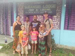 a family posing for a picture in front of a building at Subansiri lodge in Majuli