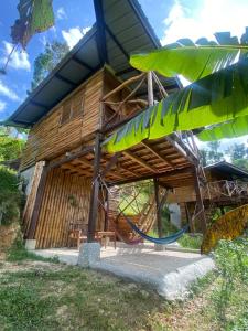 a house with a thatched roof with a playground at Green Hill Restaurant & Cottages in San Vicente