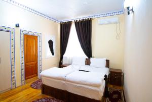 a bedroom with two beds and a window at Zaringiz Boutique in Bukhara