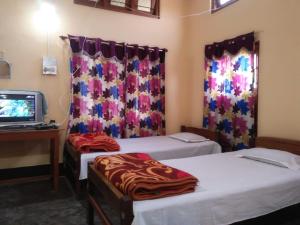 a room with two beds and a desk and a television at Subansiri lodge in Majuli